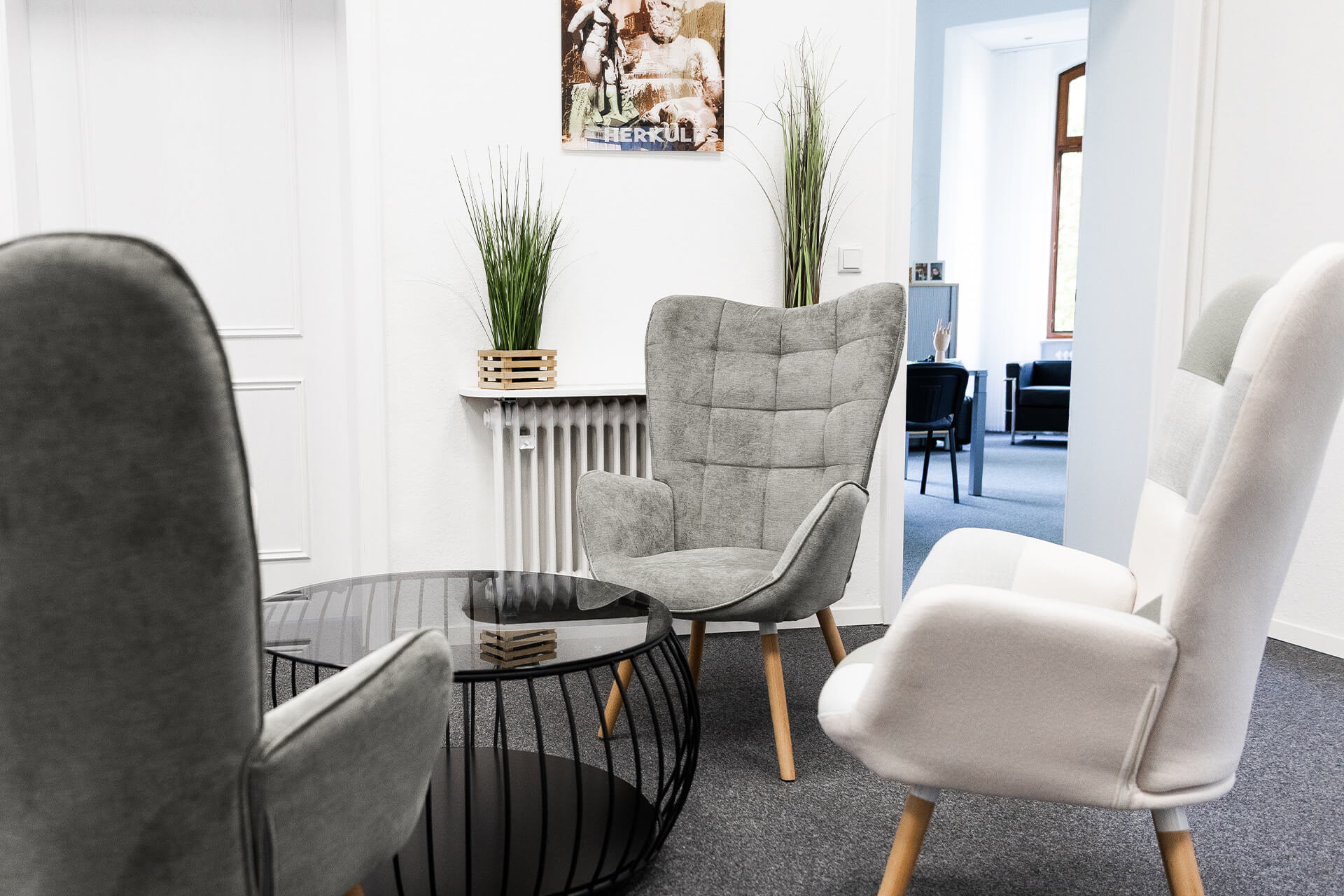 Zwei moderne Sessel in Grau und Weiß um einen runden Tisch in einem Innenraum angeordnet